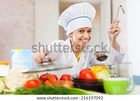 Happy professional cook in white workwear works in commercial kitchen