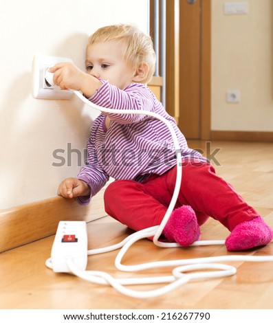 Baby girl playing with electrical extension and outlet  at home