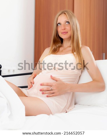 Sitting long-haired pregnancy girl in nightshirt