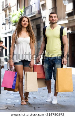 Young man and long-haired woman hunting after souvenirs in shopping tour