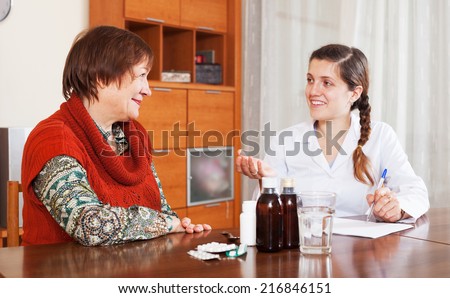 doctor prescribing medication to mature woman at home. Focus on patient