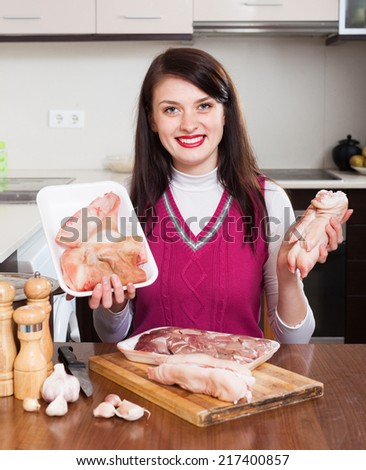 Happy woman with pork offals and meat in her kitchen