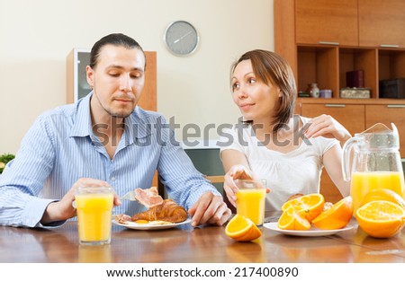 couple having breakfast with scrambled eggs and oranges in morning
