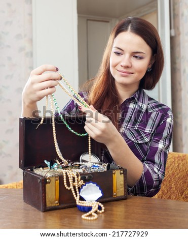girl looks jewelry in treasure chest at home