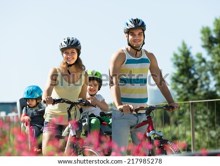 Happy smiling family with two little daughters traveling by bicycles