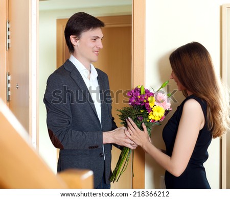 Husband present flowers to his young wife at home door