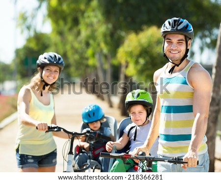 Young parents with kids in baby bicycle seats outdoor