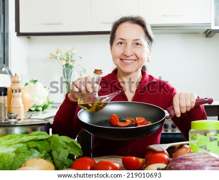 Happy  woman pouring oil into girdle at kitchen