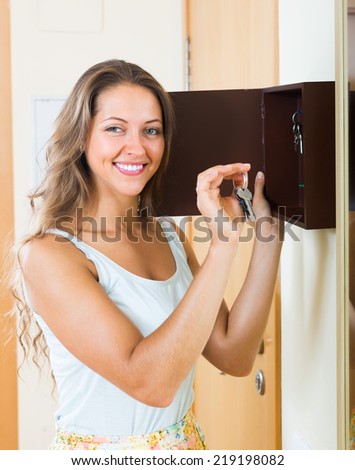 Positive smiling girl with bunch of keys staying near house-keeper