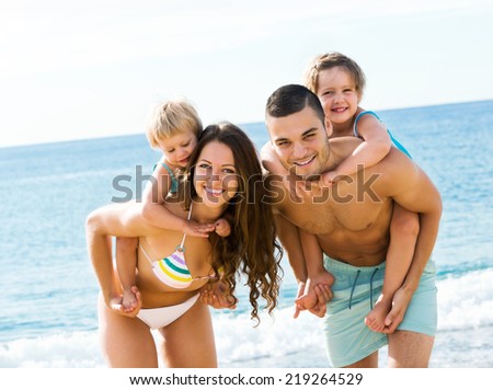 Young parents with two children walking through sandy beach