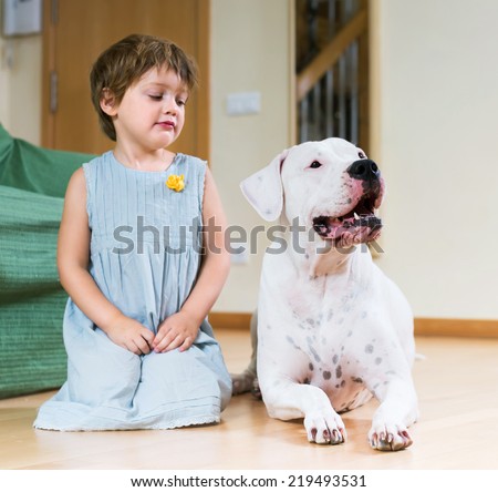 Cute little girl with big white dog lying on the floor at home. Focus on dog