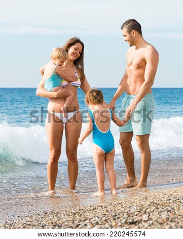 Happy young loving parents with two kids in vacation at sea shore