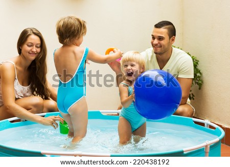 Happy children and parents playing in pool at terrace. Focus on girl