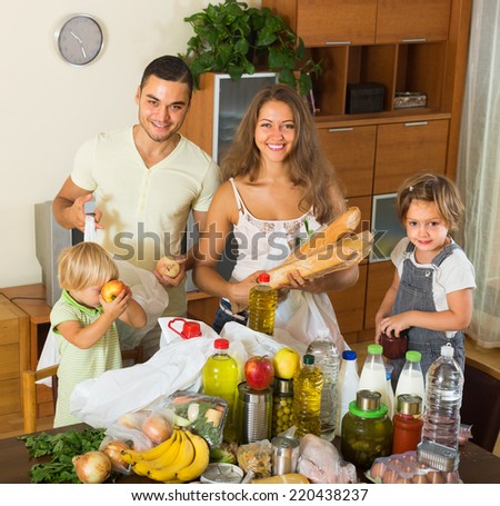 Happy smiling family with little children sorting purchased food out indoor
