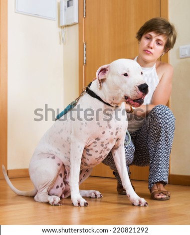 Young woman with white big dog on leash indoor. Focus on dog