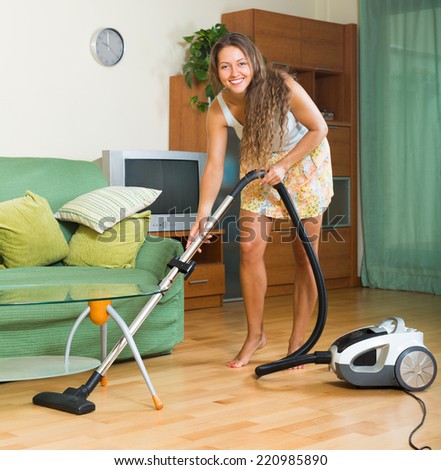 full length shot of female in skirt cleaning with vacuum cleaner at home