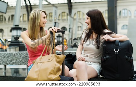 Two female friends with luggage at railway station