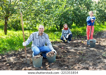 Happy family harvesting potatoes in vegetable garden