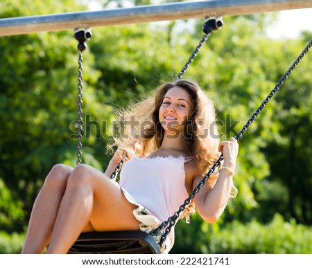 Smiling girl in skirt  on swing at park