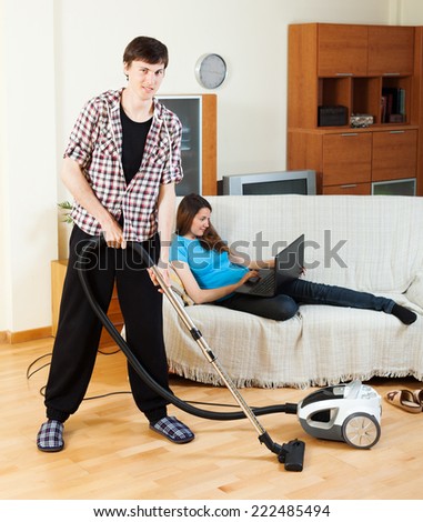 Clean up man, while wife lying with notebook on the sofa at home
