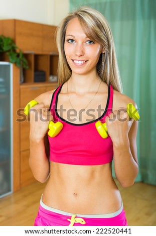 Cheerful young woman doing exercises with dumbbells at home