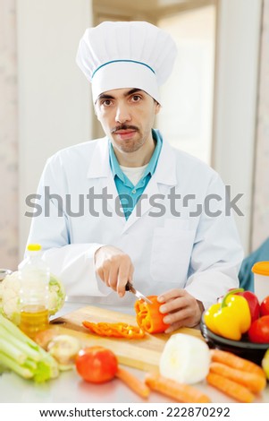 caucasian cook in uniform does veggy lunch