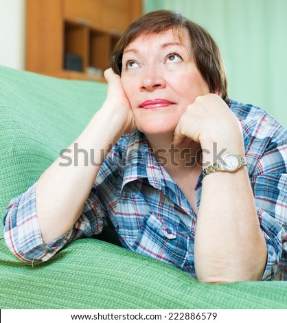 Portrait of sad mature woman having tough time and laying on couch at home
