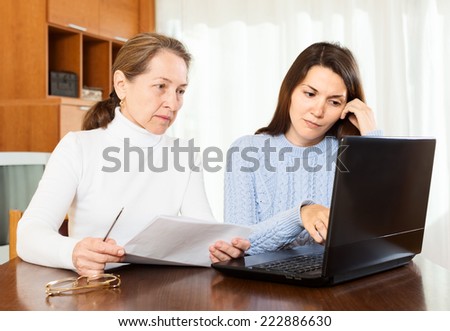 very serious  woman and young girl at table with notebook