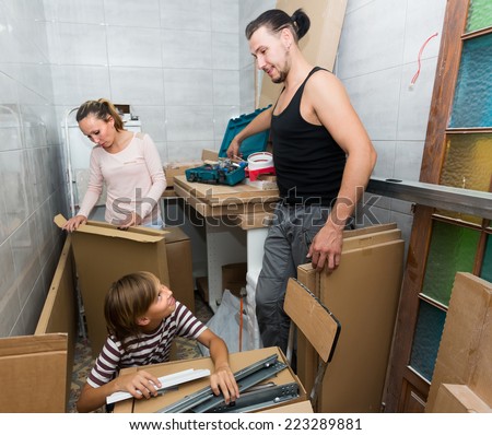 Positive family of three packing things before relocation in home basement. Focus on boy