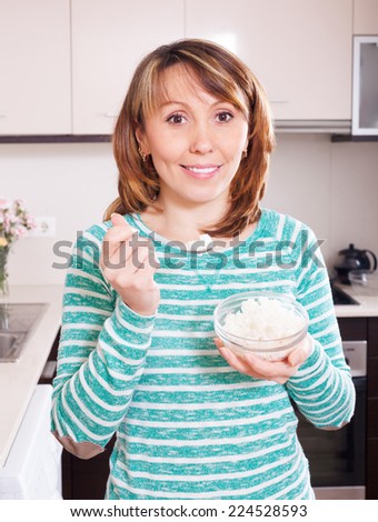 woman in green eating  rice in kitchen