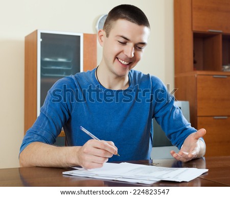 serious man  staring financial documents at table in home interior