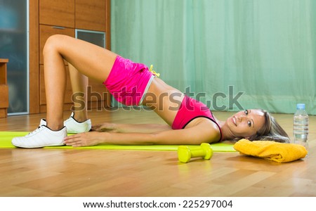 Persistent young woman training with dumbbells at home