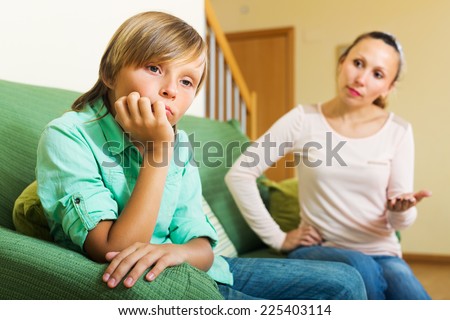 Mother scolding teenager son in living room at home. Focus on boy