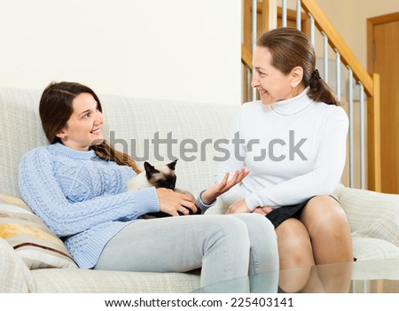 Smiling mother and  daughter  speaking about something on sofa at home