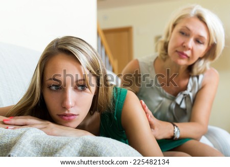 Mature mother comforting sad teenage daughter at home