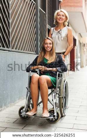 Smiling girl helping handicapped woman