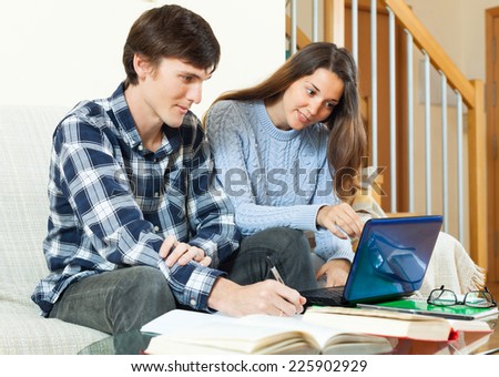 Student guy with girl preparing for session with electronic book and laptop in sofa in home
