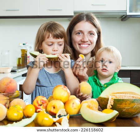 Smiling family eating melon and other fruits over  table at home interior
