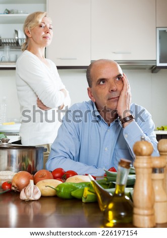 Sad senior man and  woman during quarrel  in kitchen at home