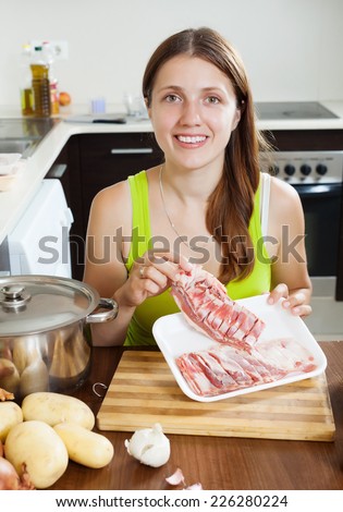 Young woman with lamb meat in her kitchen