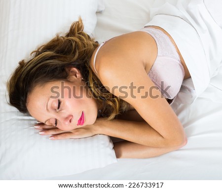 Adult woman sleeping on white pillow in bed at home