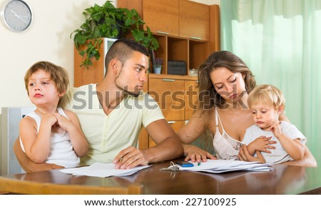 Unpleasantness about documents in young family with two kids at the table