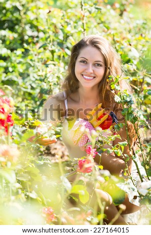 Portrait of smiling casual young woman in roses plant at garden