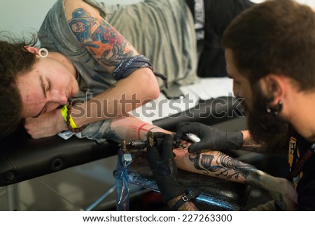 BARCELONA, SPAIN - OCTOBER 3, 2014: Professional artist  doing colorful tattoo on client arm. The 17th edition of The Barcelona Tattoo Expo in Fira de Barcelona