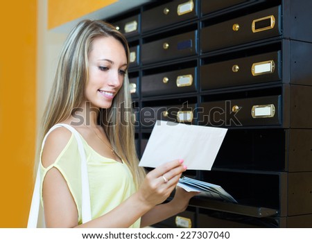 Young positive girl checking up letter-box indoor