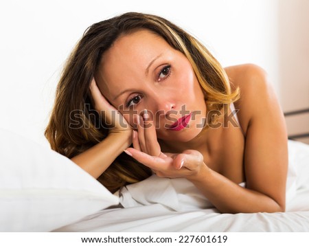 Portrait of thoughtful female with downcast eyes in bedroom