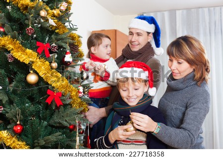 Parents with two children decorating Christmas tree at living room