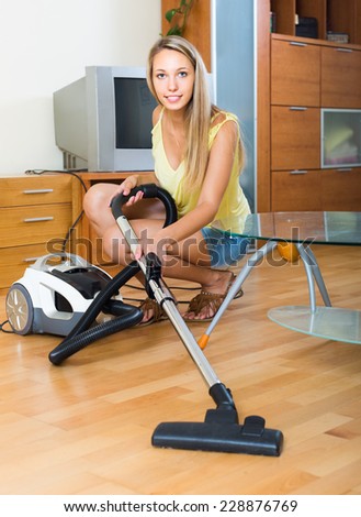 Full length shot of blonde young woman cleaning with vacuum cleaner