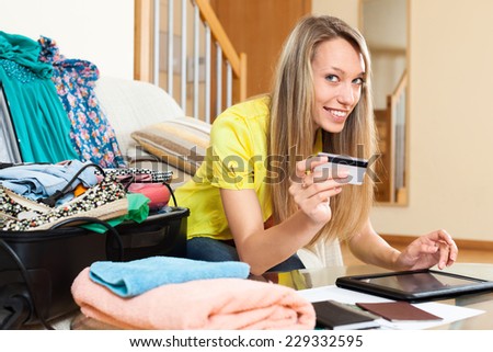 Smiling woman using credit card and tablet for reserving plane ticket