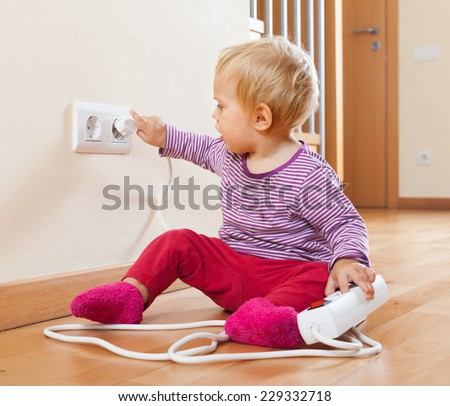 Toddler playing with extension cord and  electric outlet at home